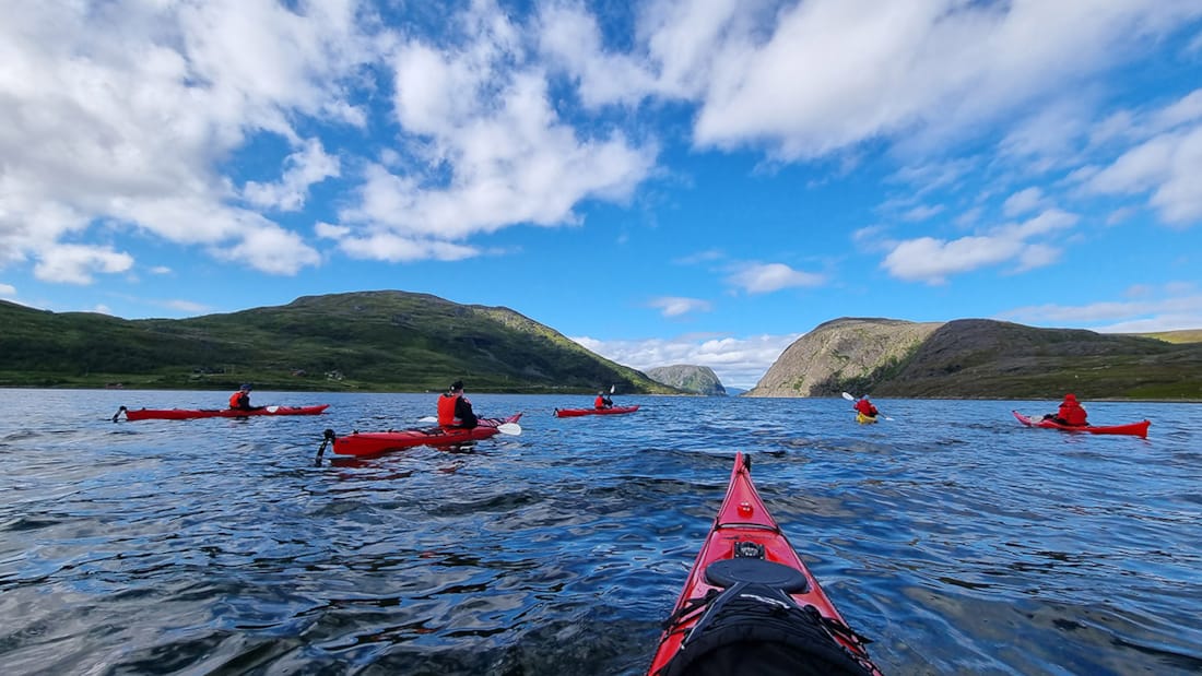 View of water and several kayaks seen from the point of view of a person sitting in a kayak
