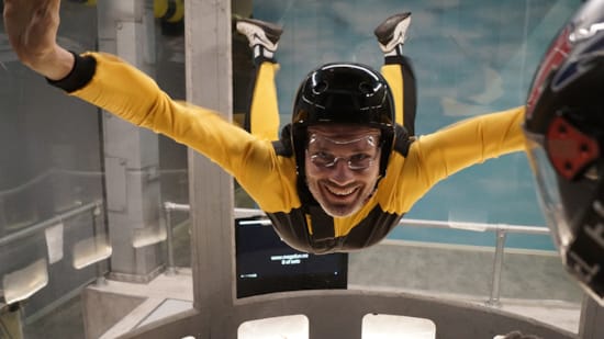 Happy man in yellow suit flying in wind tunnel