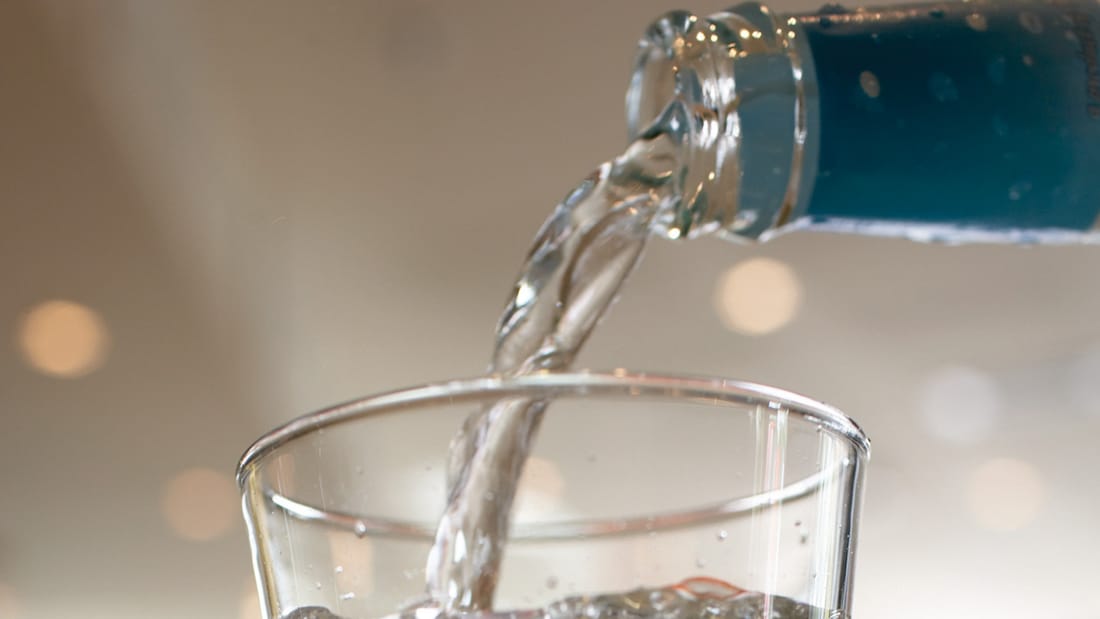 Water dat van fles naar glas wordt gegoten.
