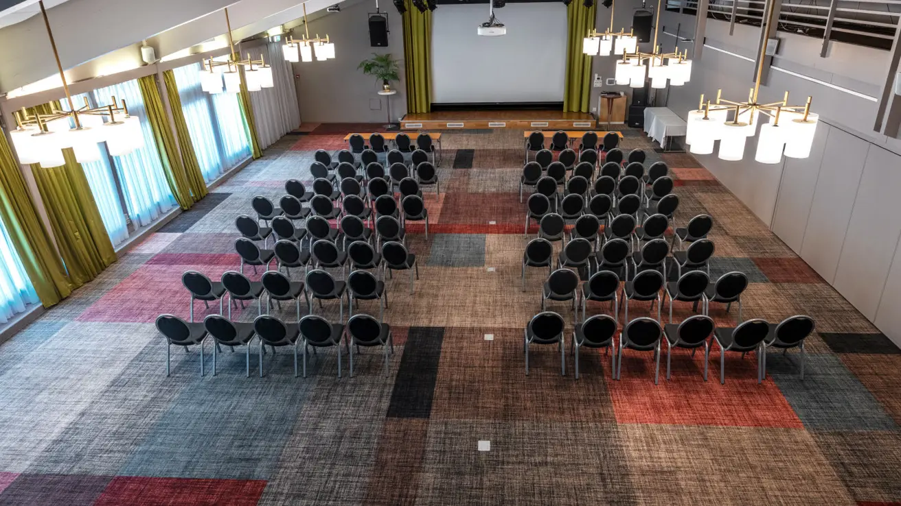 Kinooppsett, teppebelagt gulv, vinduer på langside, lerret i front.