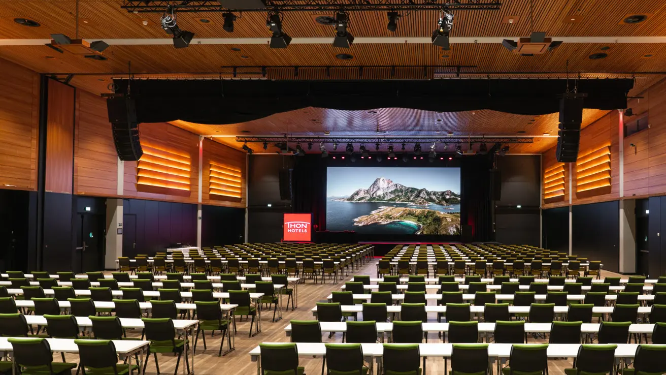 Stor konferansesal i klasseromsoppsett og med skjerm i front.